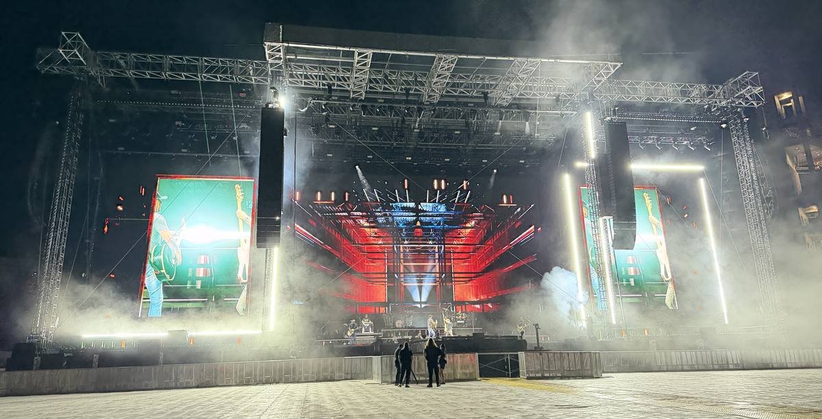 A finished stadium stage, lit and hazed, in an empty house before the crowd arrives.